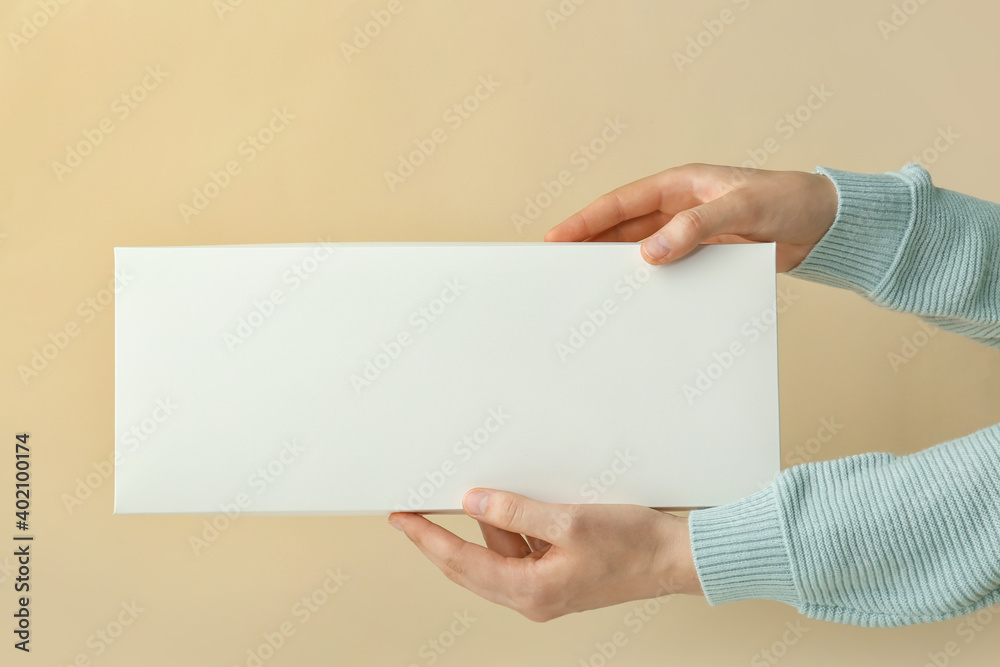 Hands with blank cardboard box on color background