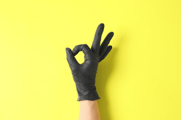 Hand in protective glove showing OK on color background