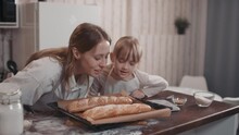 Medium Footage Of Cheerful Caucasian Mother And Little Girl In Cooking Aprons Tasting Freshly Made Bread Just Taken Out Of Oven Enjoying Smell