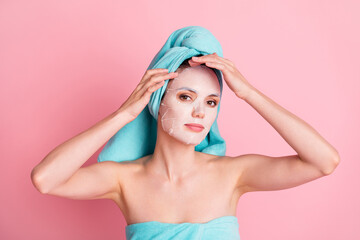 Wall Mural - Portrait of young lovely pretty happy positive girl applying moisturizing face mask wear teal turban isolated on pink color background