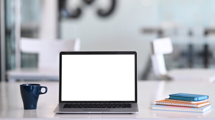 Fototapete - Mock up laptop computer with blank white screen, coffee cup and notebook on white desk in office. Blank screen for graphics display montage.