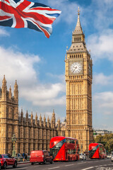 Fototapete - Big Ben with red buses on the bridge against flag of England in London, England, UK