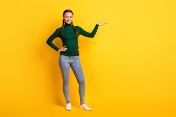 Wall Mural - Photo portrait full body view of girl showing height with hand isolated on vivid yellow colored background