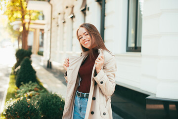 Portrait of cheerful young lady outdoor on street in city at sunset.