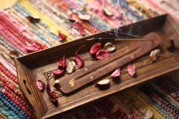 burning incense sticks on a wooden tray on a colored carpet