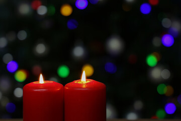 Poster - A selective focus of burning red advent candles in front of colorful bokeh lights