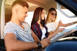 © New Africa - Happy friends with map in car on road trip