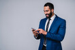 © InsideCreativeHouse - Intelligent Arab businessman in formal outfit using mobile phone isolated over grey background