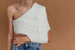 Yuong boy on a beige isolated background with a back, collarbone or shoulder injury. Medical care for fracture of the clavicle.