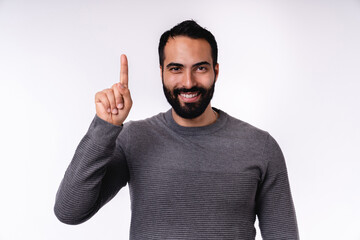 attractive smiling arab man in casual attire pointing at copy space isolated over white background