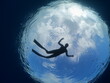 © underocean - free diver silhouette underwater with sun and clous in the sky ocean scenery