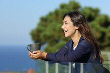 Happy Woman With Coffee Mug Contemplates Views From Balcony
