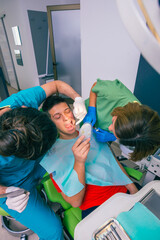 Wall Mural - Male dentist with the help of a female dentist examines the mouth and teeth of a teenage boy patient.