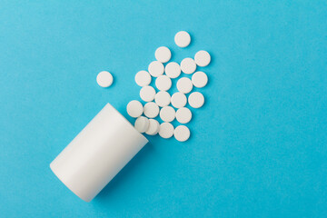 White tablets and bottle for tablets on blue background