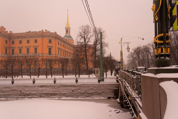 The Moyka River, the First Garden Bridge and a view of the Mikhailovsky Castle in St. Petersburg, a snowy gloomy December. Winter in St. Petersburg in Russia