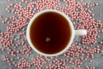 A white cup of hot tea with pink sprinkles