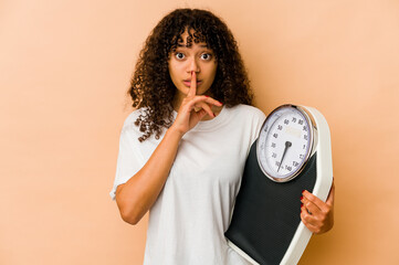 Young african american afro woman holding a scale keeping a secret or asking for silence.