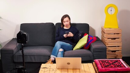 Poster - A woman uses a phone in her hands before broadcasting a webinar in the room. Using a camera to transmit information to subscribers. Communication with a wide audience.