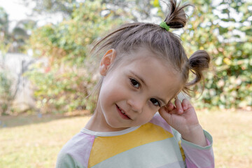 Cute little girl walks on nature and laughs and grimaces looking into the camera. happy childhood and positive emotions. 