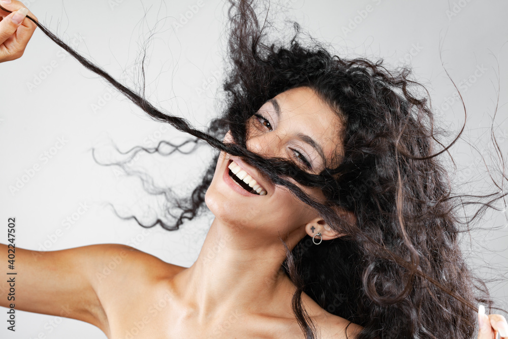 Beautiful brunette girl with long curly hair in the air, studio ...