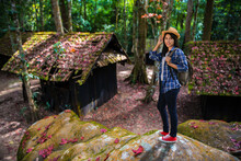 Female Tourist With A Backpack Standing On A Rock In Hand In The Green Forest At Political And Military School At Phu Hin Rong Kla National Park, Spring Time, Phitsanulok Province, Thailand