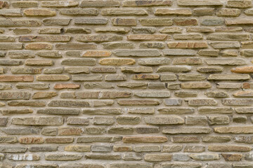 texture of bricks on the wall in the form of wild stone Background. Beige and brown tones with shadows and deep texture. Facing stone for wall background.