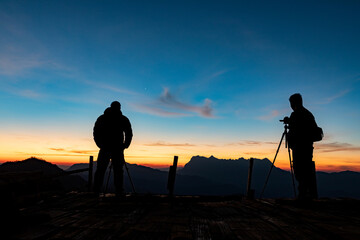 Wall Mural - silhouette photographer take photos early morning mountains view with smooth orange blue gradient of