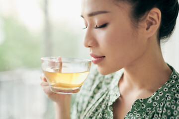 Beautiful young woman is looking out the window and holding a cup of tea