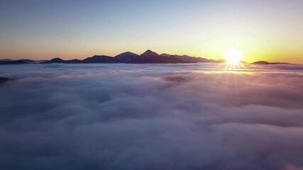 Wall Mural - beautiful aerial sunset above foggy clouds in mountains nature drone shot hyper lapse