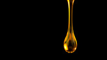 Pouring Oil Drop Isolated On Black Background. Macro Shot.