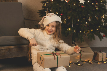 Wall Mural - Gifts under the tree. Children rejoice delighted with Christmas But