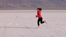 Asian Woman Jogging Across The Bonneville Salt Flats Flats In Utah. Slow Motion.