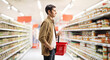 © Ljupco Smokovski - Guy in a supermarket carrying a red shopping basket and looking at products on shelves