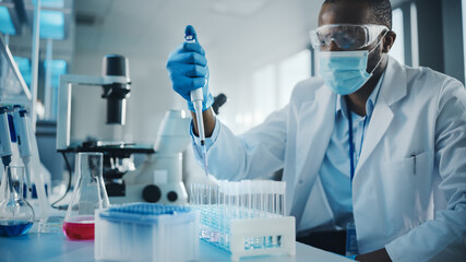 Medical Development Laboratory: Black Scientist wearing Face Mask Uses Pipette for Filling Test Tube with Liquid, Conducting Experiment. Pharmaceutical Lab with Medicine, Biotechnology Researchers