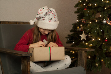 Wall Mural - The girl opens Christmas gifts with a Christmas tree. Happy New Year. Surprises