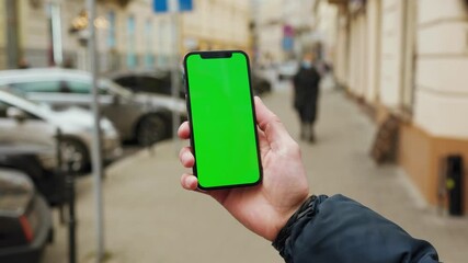 Shot of hands man using phone with vertical green screen background street with tree city blurred internet chrome outdoor. Cellphone media device. Slow motion