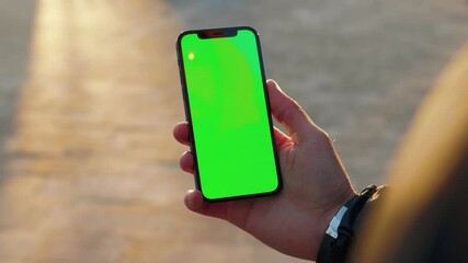close up man young hand using touch phone with vertical green screen background sunlight road in cit