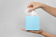 © New Africa - Woman taking paper tissue from box on light background, closeup. Space for text
