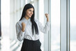 © F8  \ Suport Ukraine - Young businesswoman standing celebrating her winning in front office panoramic window