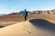 © Ron - A hiker person man hiking on a sand dune leaving a track as he goes with a ridgeline clearly visible, no wind, Eureka Dunes, Death Valley National Park, California