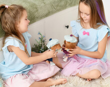 Little Kid Girls Sisters In Blue Dresses Play Together With Their Dolls Talking Meeting On Soft Carpet Rug At Home. Happy Childhood, Cheerful Lifestyle, Games, Comfortable Pastime, Hobby Concept