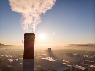 Drone view of a factory chimney with smoke and buildings