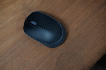 Black computer mouse in the wooden table