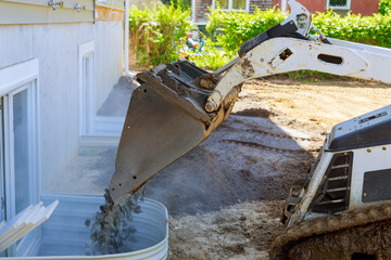 Wall Mural - New house under construction window well basement construction bucket standing on gravel stones