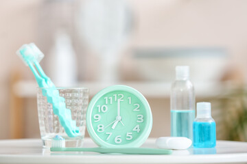 Alarm clock and set of oral care products on table