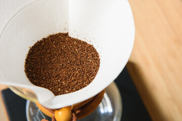 Drip or brewed coffee with paper dripping, grinder and coffeepot on wooden texture