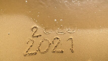 Wall Mural - message year 2020 replaced by 2021 written on beach sand background. good bye 2020 hello to 2021 lap