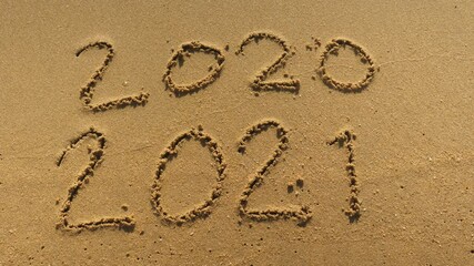 Wall Mural - message year 2020 replaced by 2021 written on beach sand background. good bye 2020 hello to 2021 lap