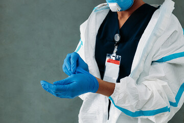 Wall Mural - Mid section of unrecognizable female doctor takes off medical gloves at a wall