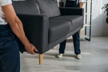 Wall Mural - partial view of workers carrying heavy sofa in apartment